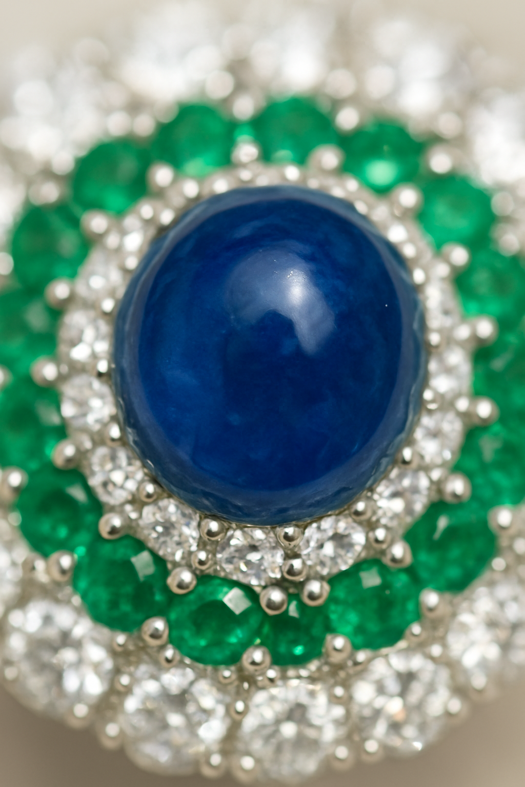 Macro shot of cabochon sapphire gemstone ring with emeralds and diamonds