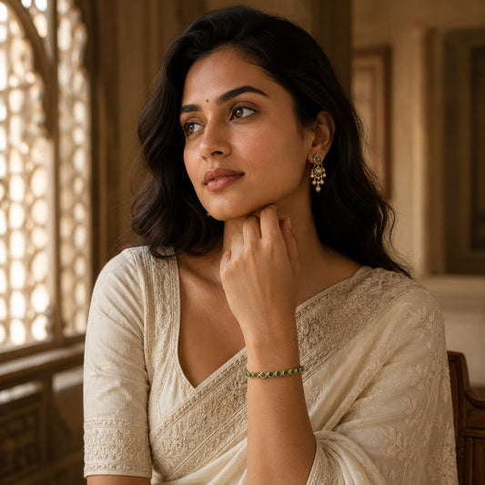 Woman wearing emerald bezel bracelet with cream saree and matching earrings
