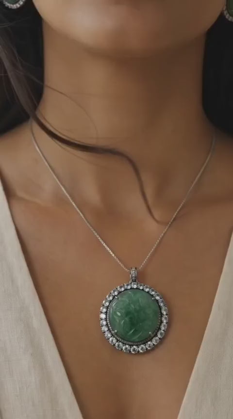 Close-up of hand-carved green beryl pendant with diamond halo