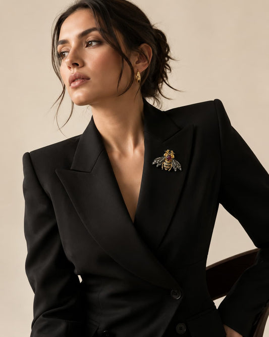 Woman wearing gold and black bumble bee brooch with ruby on black blazer lapel
